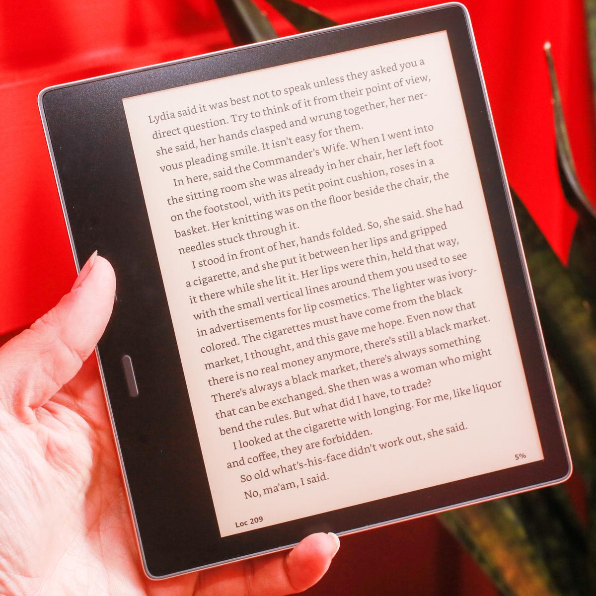 mężczyzna w fotelu czytający książkę na czytniku e-booków przy stoliku z kawą